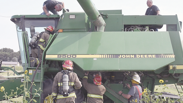 Lovell volunteer firemen and owner Michael Leonhardt check out an overheated combine in a field west of Caboose Park and Rose City West Thursday afternoon. David Peck